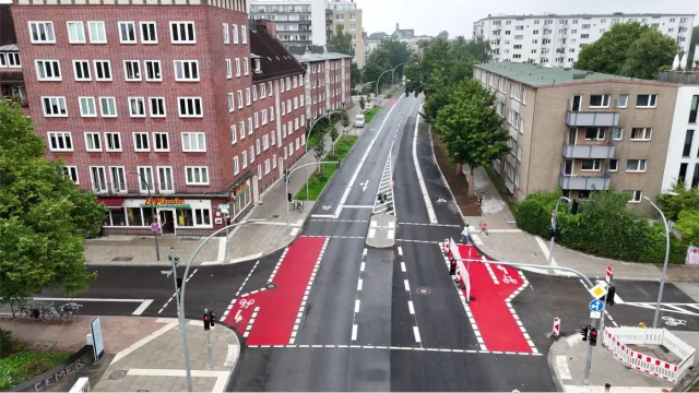 Königstraße in Hamburg mit blau-grüner Infrastruktur: breite, teilweise geschützte Fahrradstreifen entlang der Fahrbahn. © BVM / Robin Lindner Königstraße in Hamburg mit blau-grüner Infrastruktur: breite, teilweise geschützte Fahrradstreifen, begleitet von Bäumen und Grünstreifen.